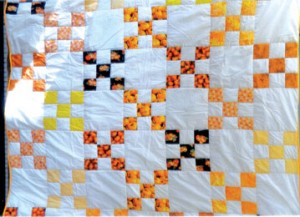 This “Nine Patch” Pumpkin Quilt was designed by Susie Flowers and quilted by Ann Stowe.