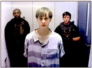 Photo courtesy Charleston Post and Courier Emanuel AME Church shooting suspect Dylann Roof appears via video before a judge during a hearing following his arrest last week.