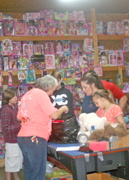 Ben Robinson/Courier As toys line the shelves, volunteers — also known as elves — help at Country Santa’s workshop in Pumpkintown on Saturday. “To tell the truth, we would be lost without our volunteers,” organizer Buddy Cox said. 